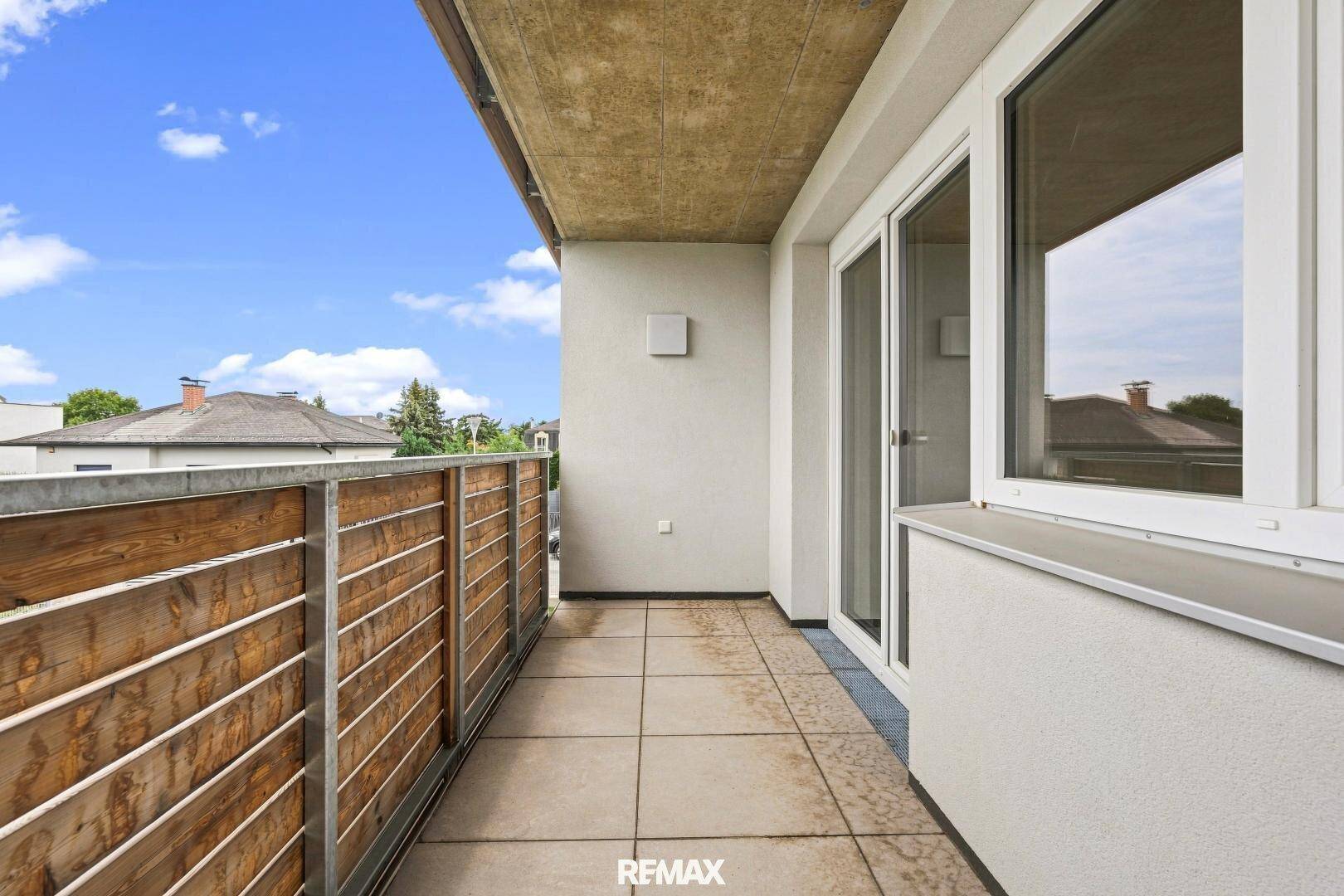 Langer Balkon mit Fliesen und Holzgeländer, ideal für Entspannung im Freien mit Weitblick.
