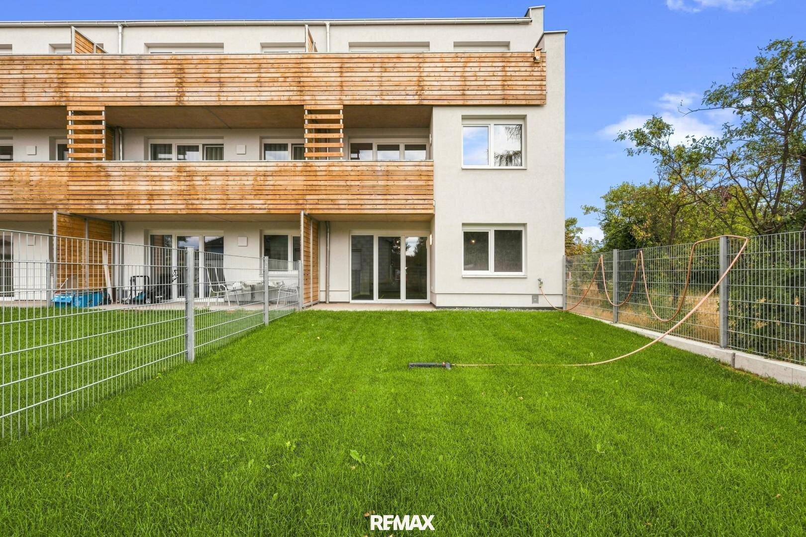 Gepflegter Rasenbereich im Garten vor der modernen Wohnanlage mit Terrassenzugang.