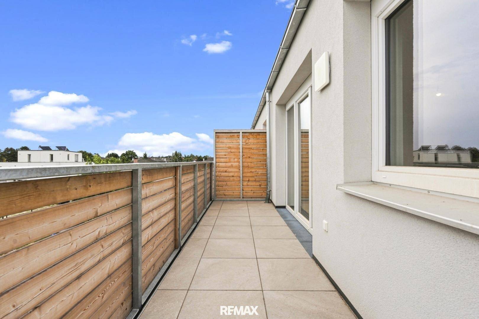 Moderner Balkon mit Fliesen und Holzgeländer, bietet einen schönen Ausblick auf die Umgebung.