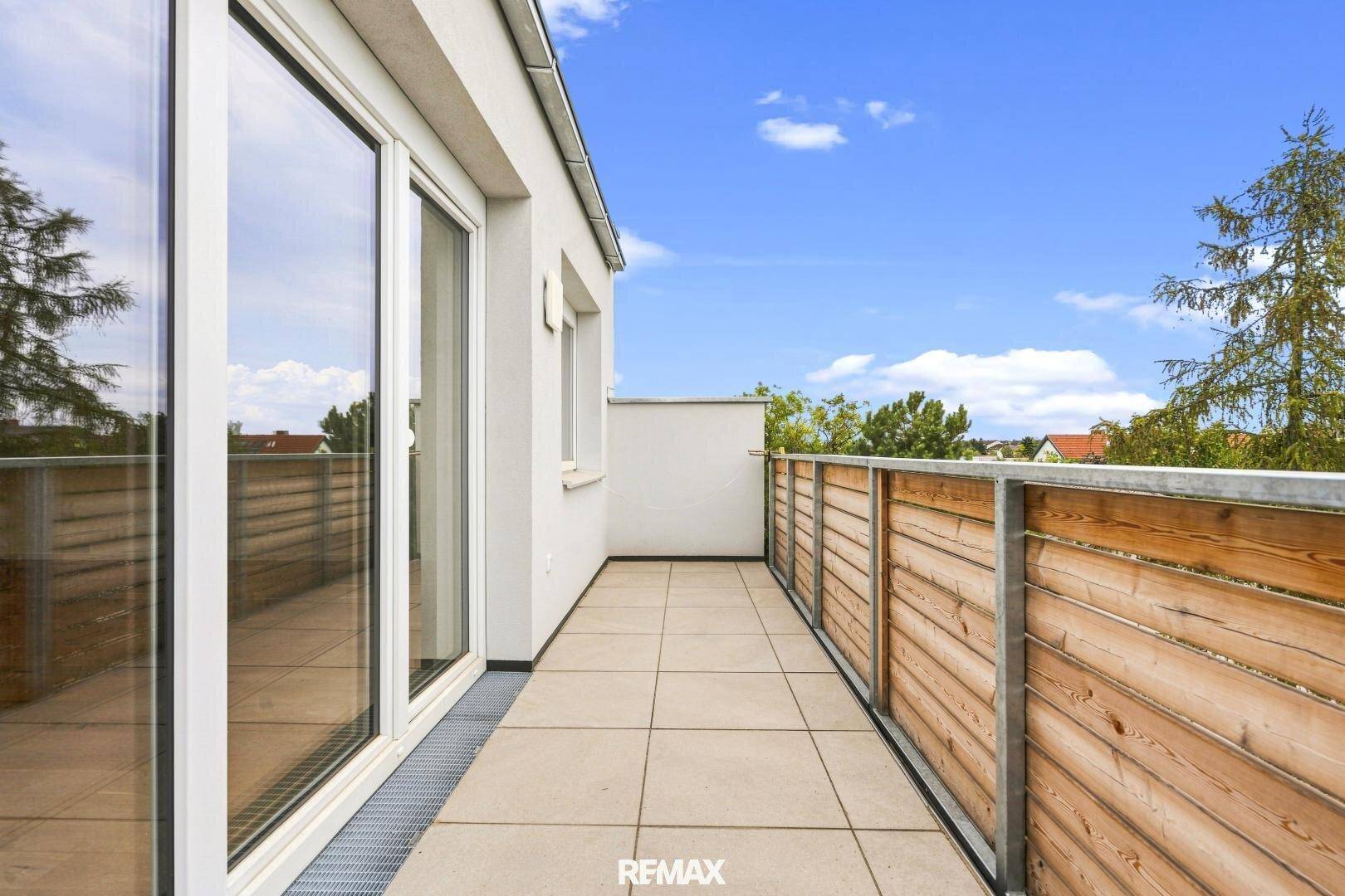 Langer Balkon mit Fliesenboden und Holzverkleidung, ideal für entspannte Stunden im Freien.