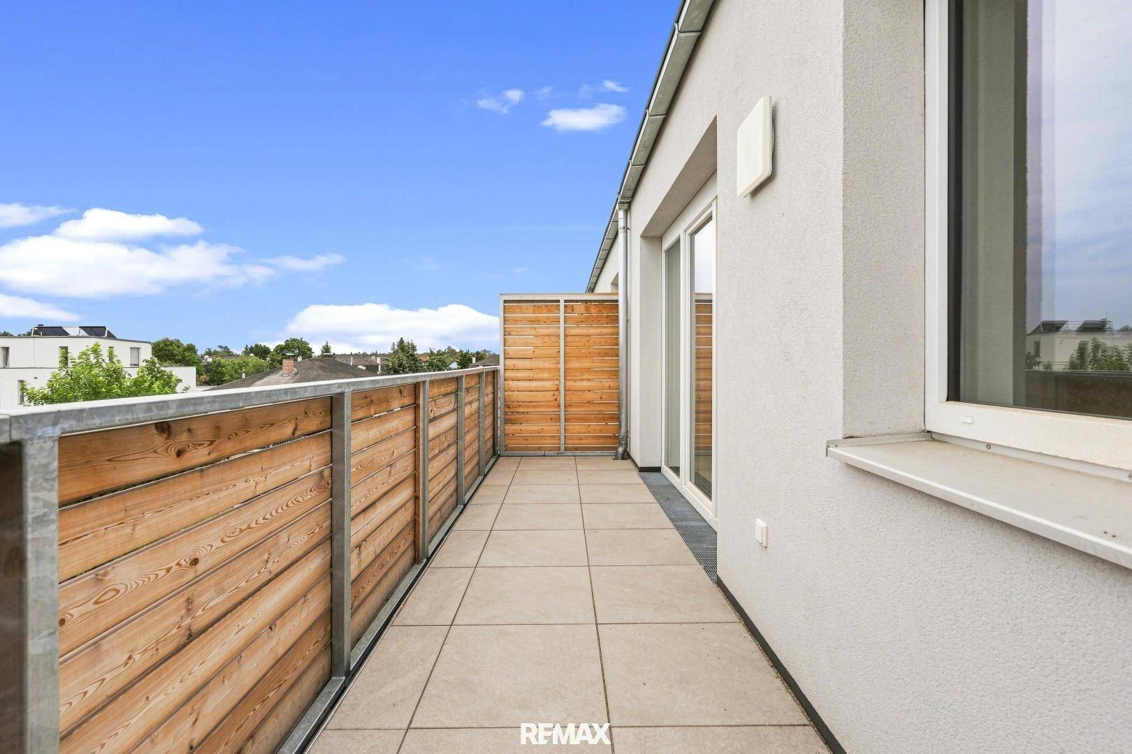 Geräumiger Balkon mit Fliesen und Holzgeländer, bietet Platz für Outdoor-Möbel und einen schönen Ausblick.
