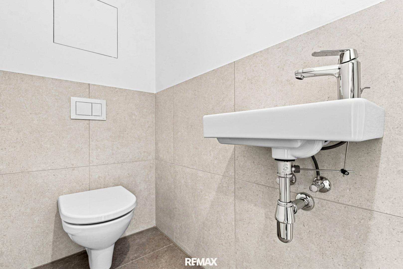 Modernes Gäste-WC mit Wand-WC, kleinem Waschbecken und hellen Fliesen, praktisch und platzsparend.
