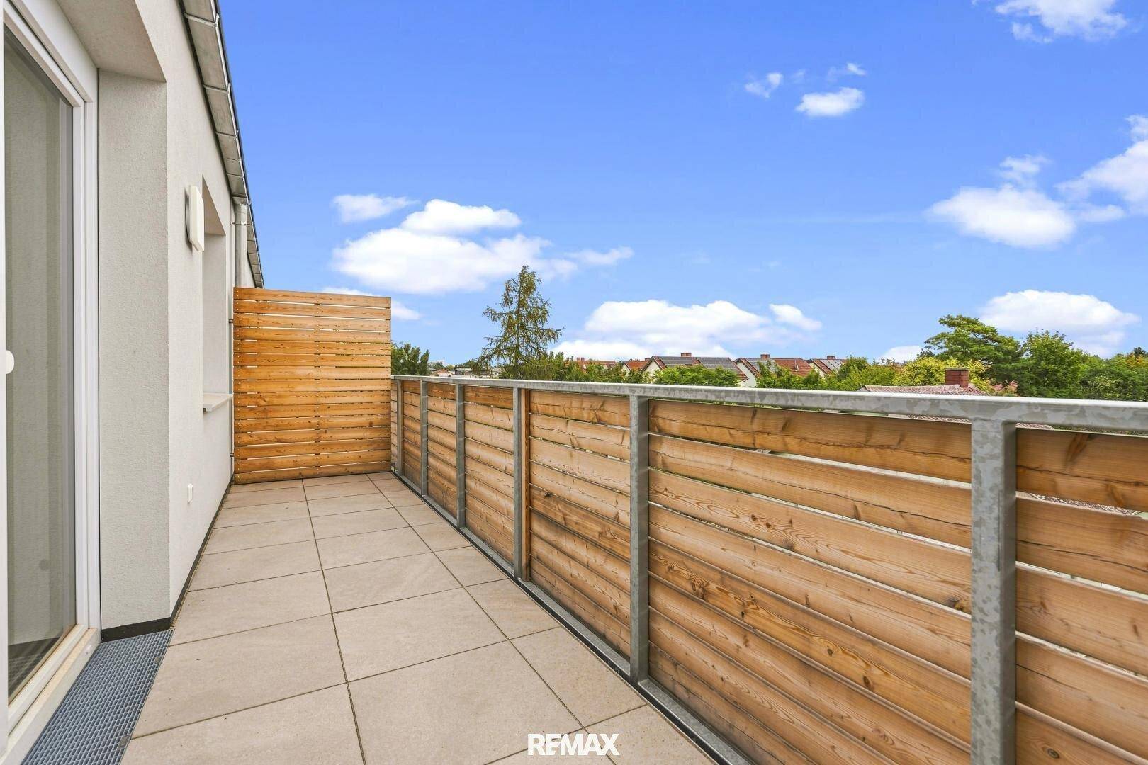 Langer Balkon mit modernen Fliesen und Holzgeländer, ideal für Entspannung im Freien.