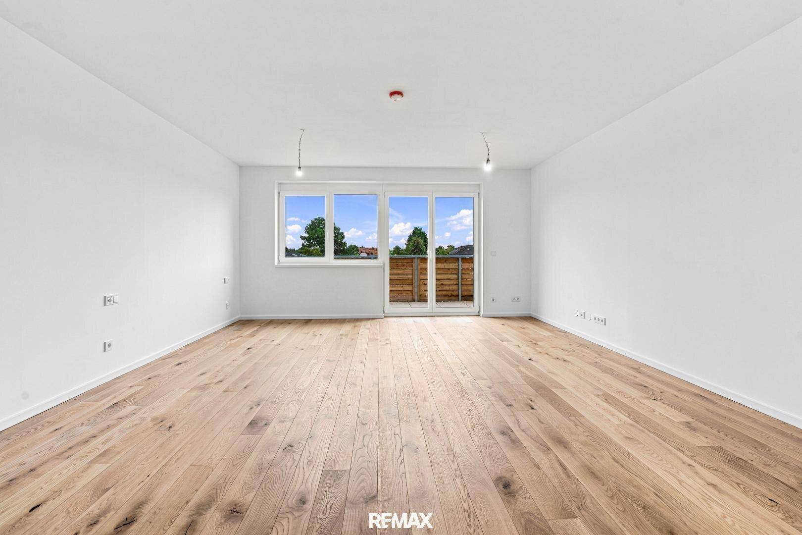 Heller, leerer Raum mit Eichenholz-Dielenboden und Zugang zu einem Balkon.
