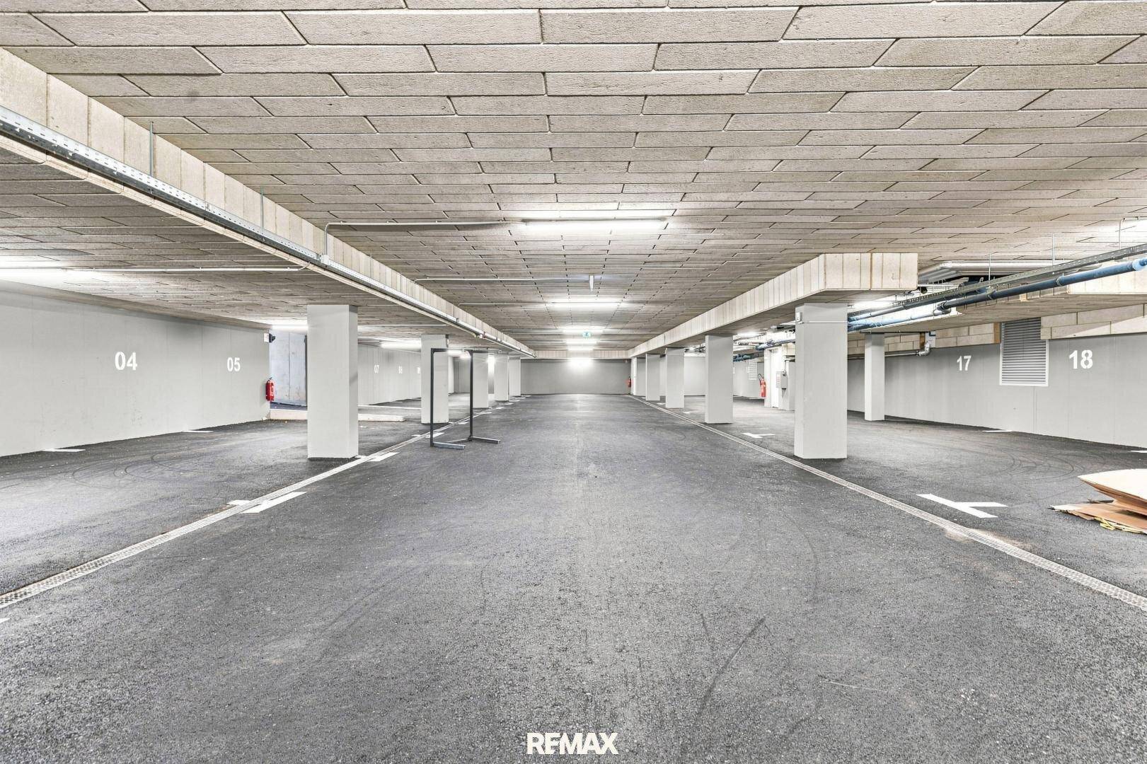 Geräumige Tiefgarage mit nummerierten Stellplätzen und moderner Beleuchtung.