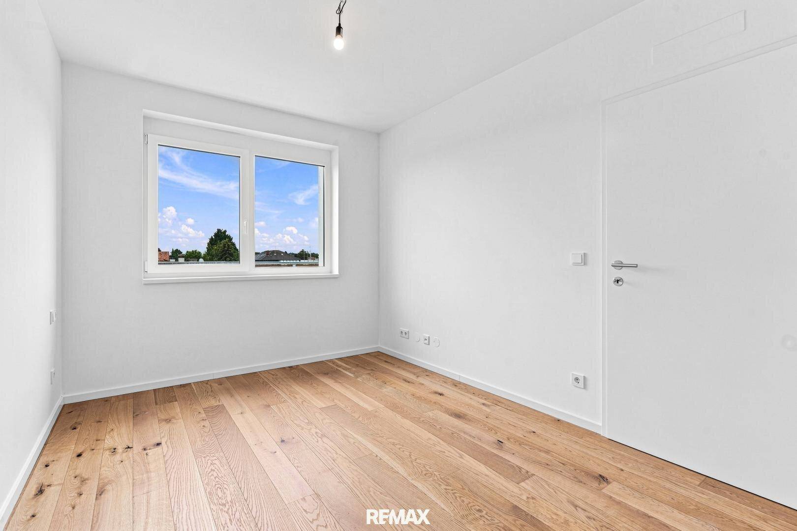 Helles Zimmer mit Holzboden und weißer Tür, bereit zur individuellen Gestaltung.