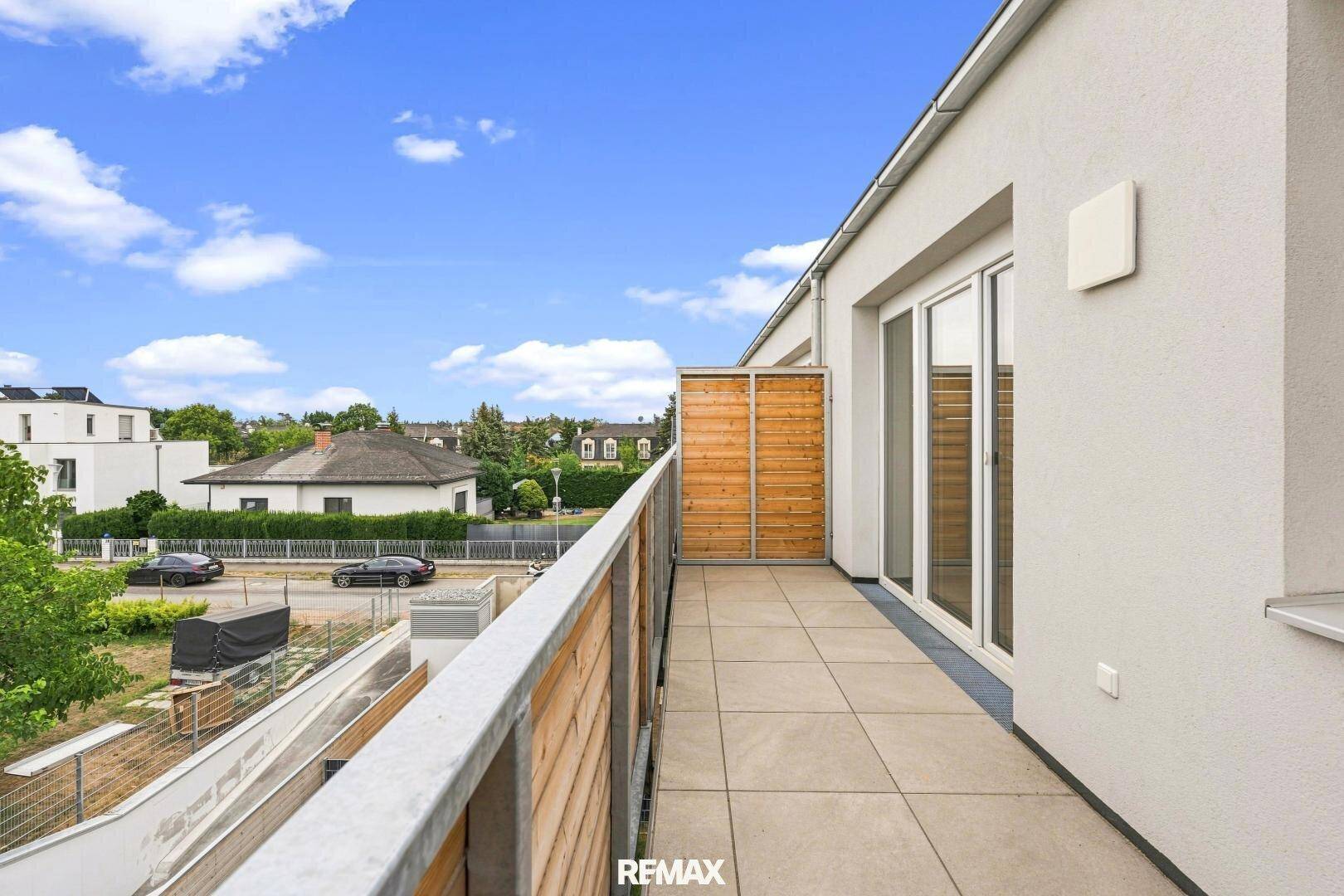 Langer Balkon mit Holzelementen und Blick auf die umliegende Nachbarschaft.