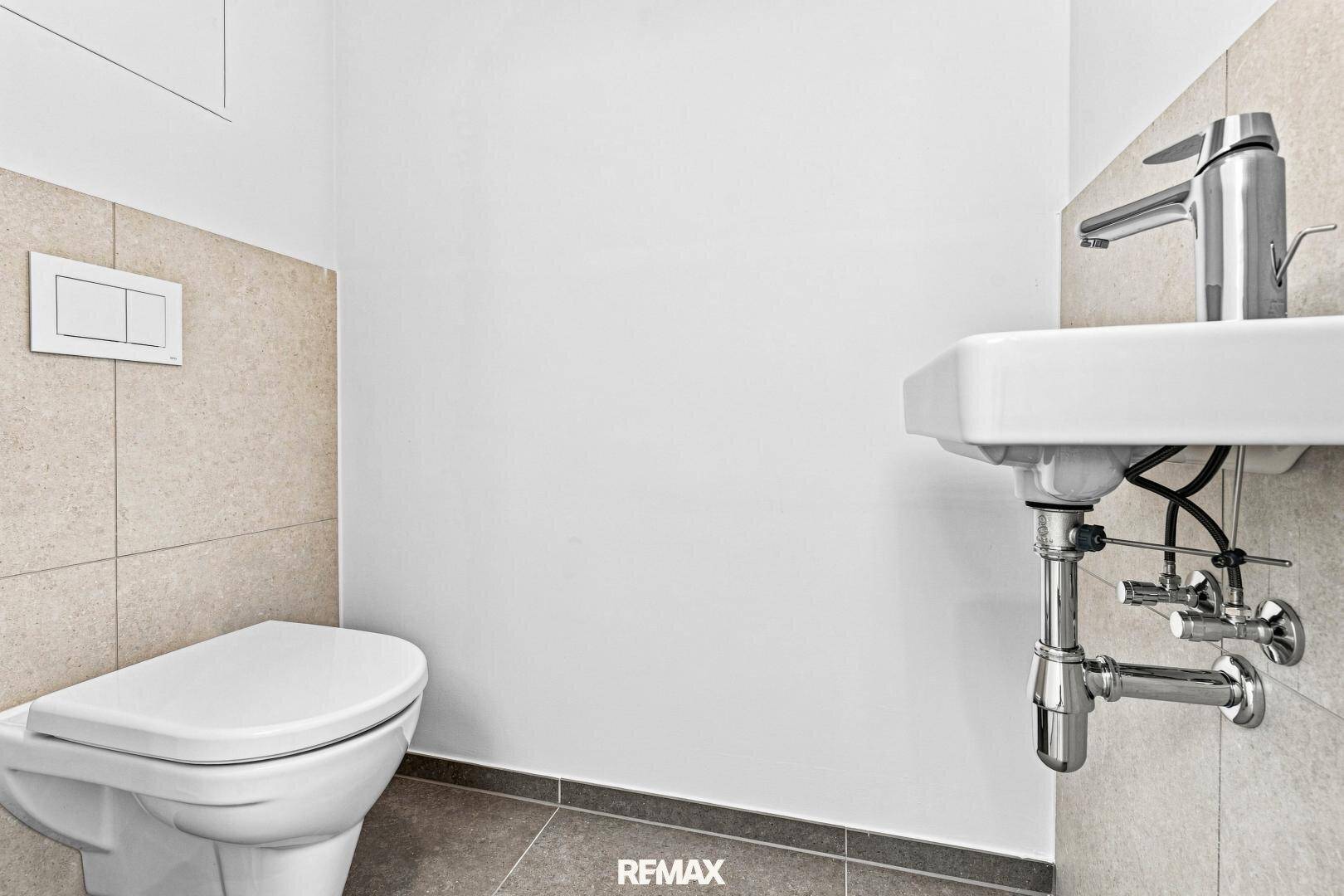 Separates WC mit wandhängender Toilette und kleinem Waschbecken in modernem Design.