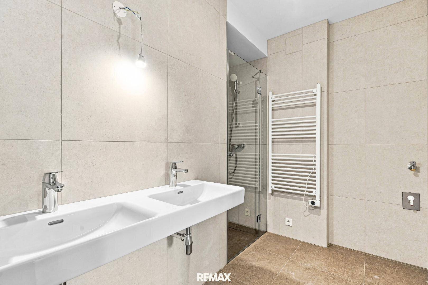 Geräumiges Badezimmer mit Doppelwaschbecken, ebenerdiger Dusche und beheiztem Handtuchhalter.