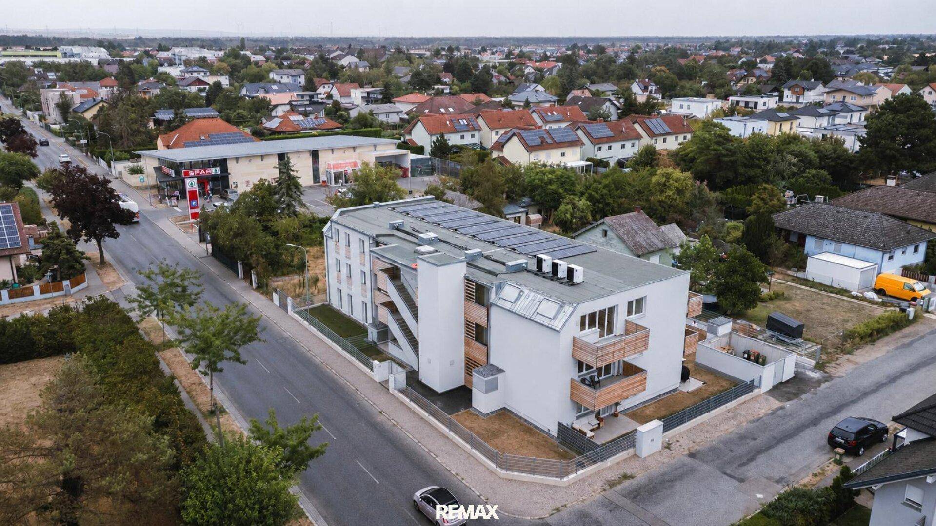 Gesamtansicht des Neubaus aus der Luft, umgeben von Wohnbebauung und weitläufigen Grünflächen.
