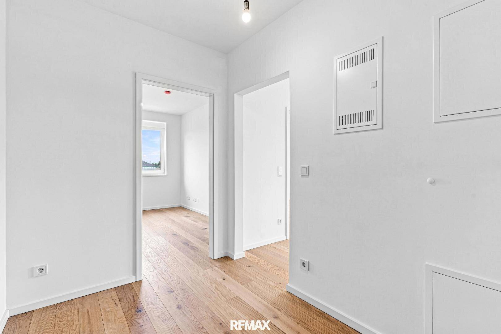 Heller Flur mit Holzboden und offenen Türen, die zu verschiedenen Zimmern der Wohnung führen.