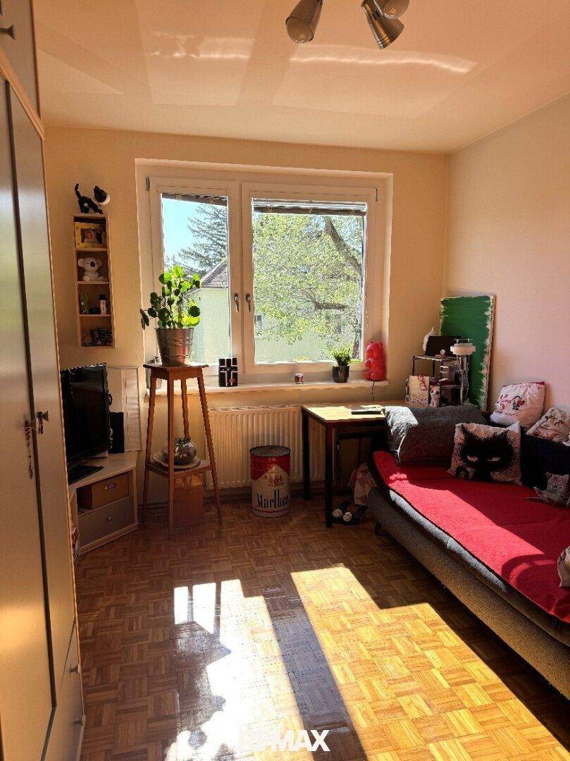 Gemütliches Schlafzimmer mit Parkettboden, Fenster und viel Tageslicht, einladend gestaltet.
