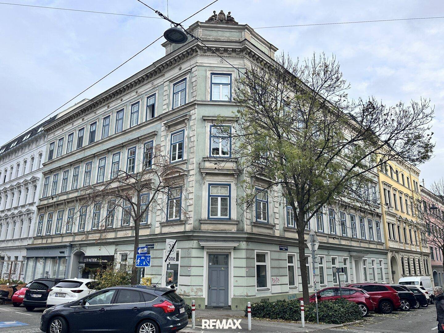 Historisches Eckgebäude mit klassischer Architektur und vielen Fenstern in einer urbanen Umgebung.