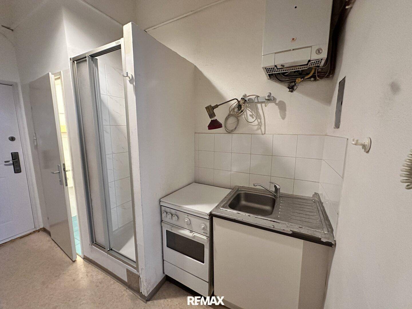 Kompakte Küchenzeile mit Spüle, Herd und Warmwasserbereiter, ideal für kleine Wohnungen.