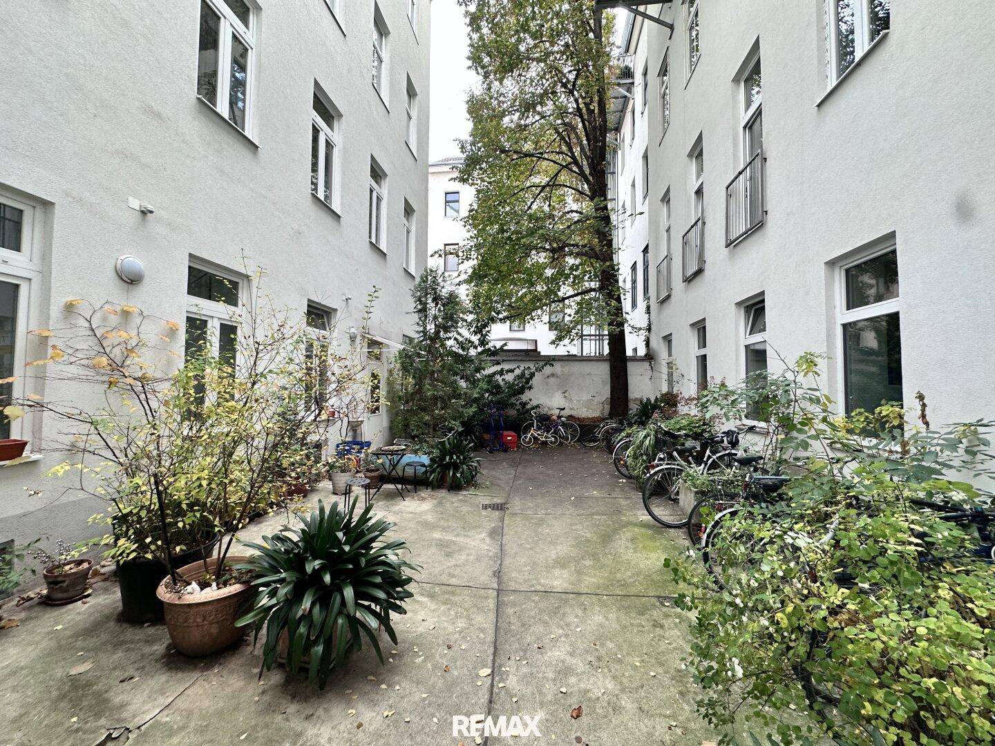 Grüner Innenhof mit Pflanzen und Fahrradstellplätzen, umgeben von Wohngebäuden.