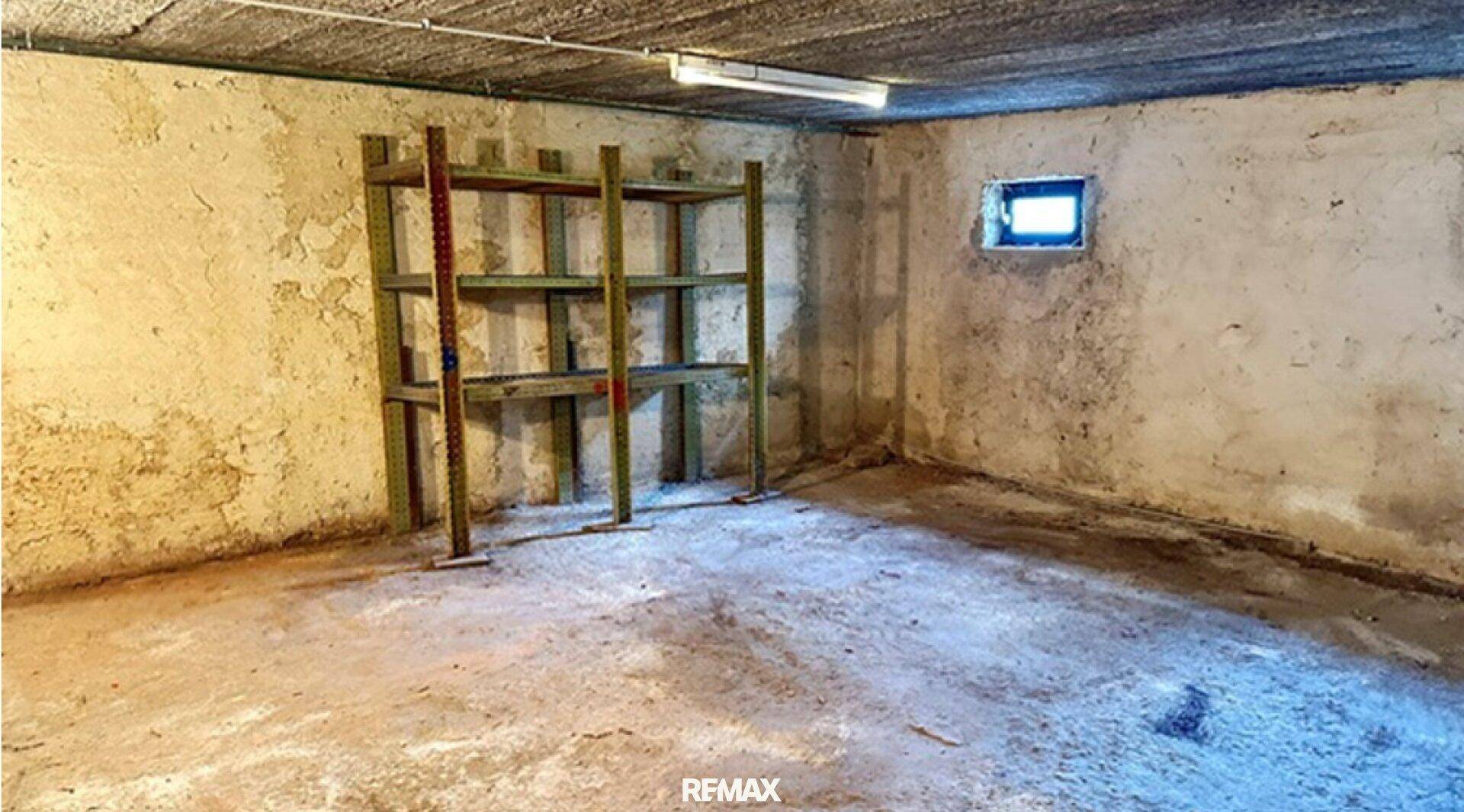 Unfertiger Kellerraum mit Betonboden und kleinem Fenster, ideal als Lagerraum.