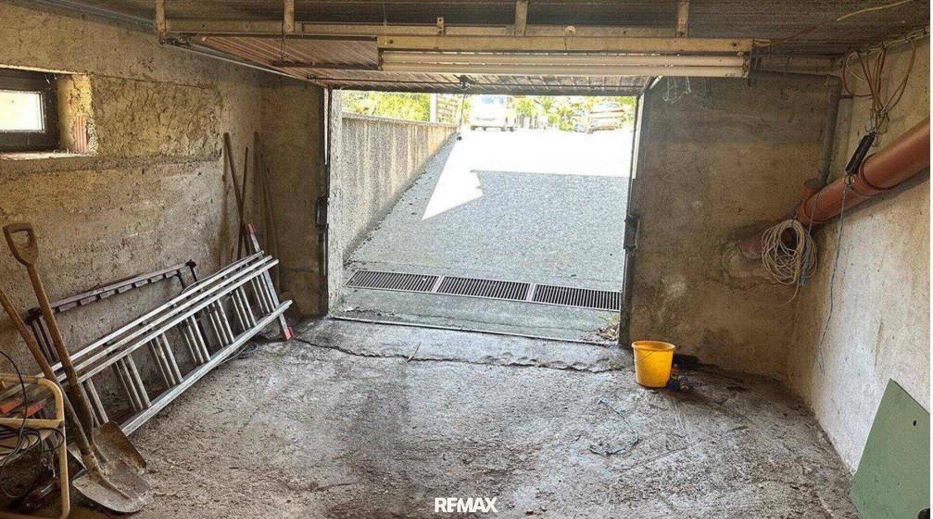 Garage mit Betonboden und direktem Zugang zur Auffahrt, ideal für Fahrzeuge.