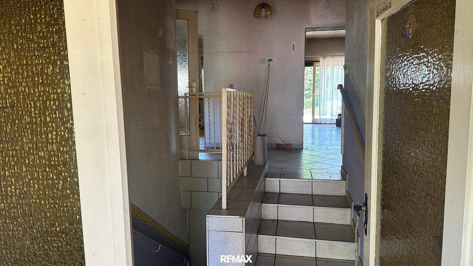 Flur mit gefliesten Treppen und Zugang zu verschiedenen Räumen im Haus.