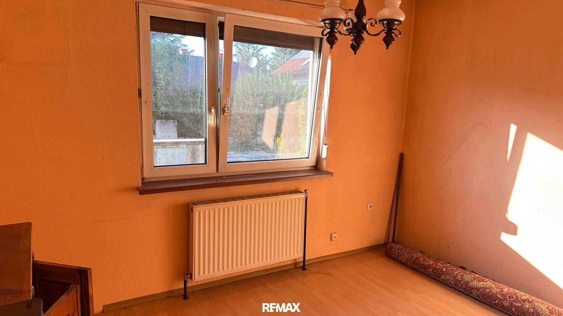 Helles Zimmer mit Laminatboden und Fenster, das viel Sonnenlicht hereinlässt.