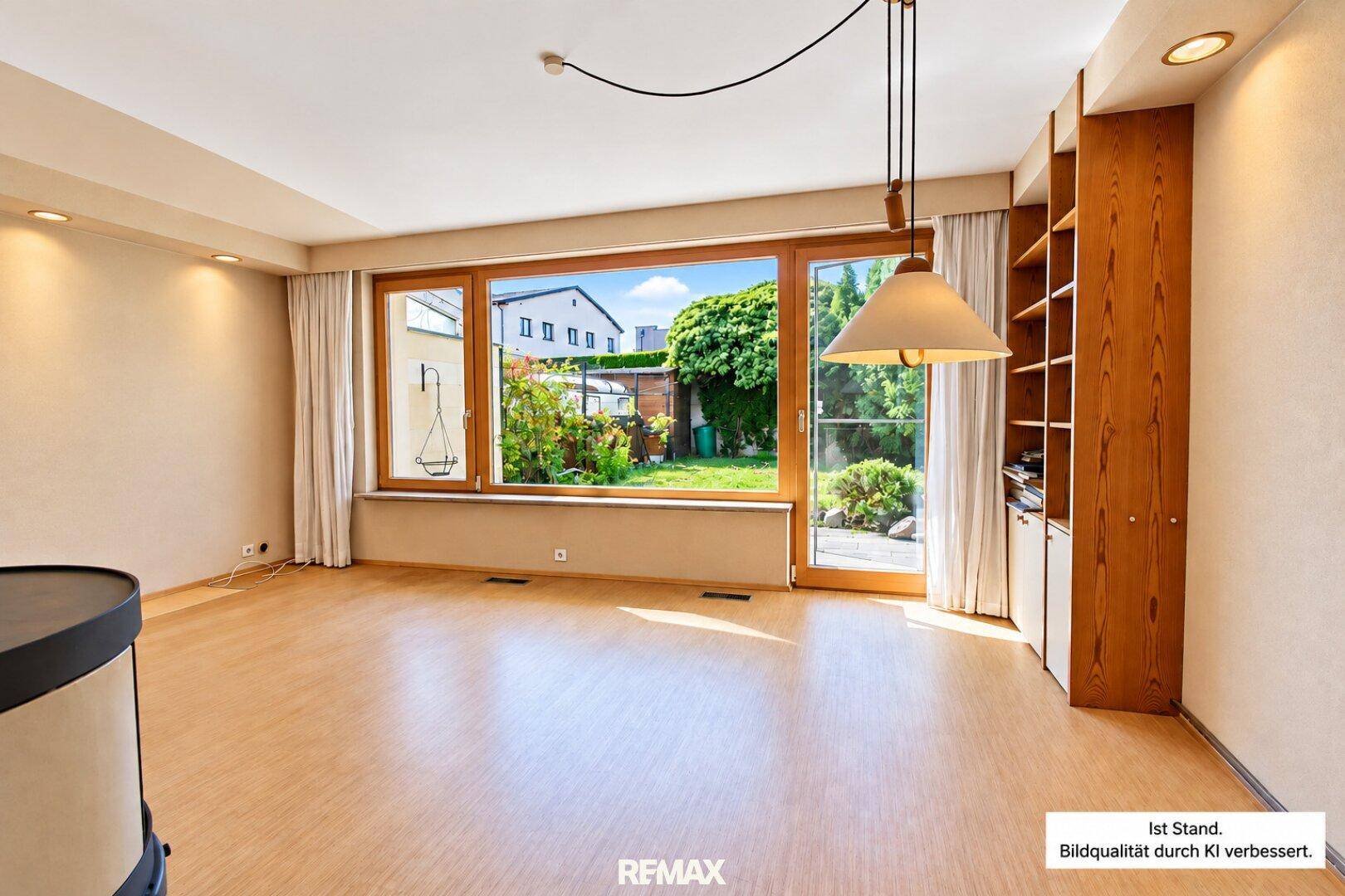 Geräumiger Wohn-Essbereich mit Holzfußboden, großen Fenstern und Zugang zum Garten.
