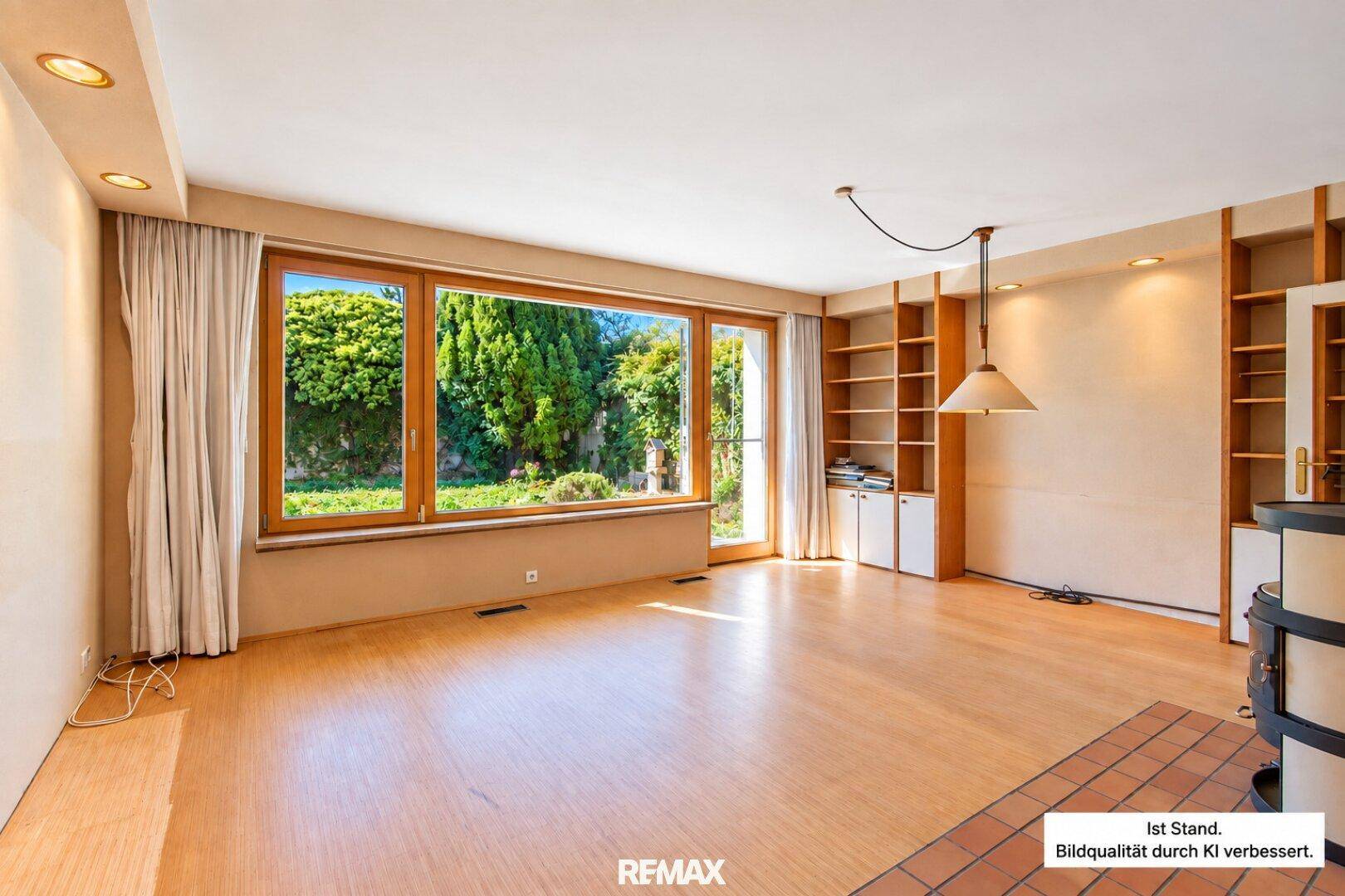 Heller Wohn-Essbereich mit Parkettboden, Kamin und großen Fenstern zum Garten.