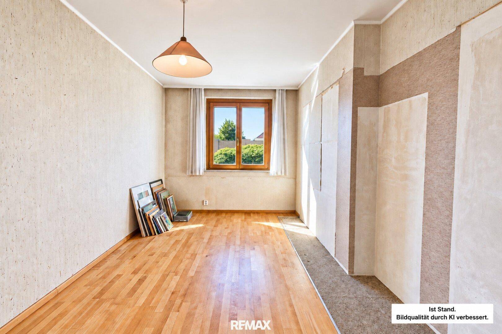 Leeres Zimmer mit Holzfußboden, Tapeten und Fenster mit Blick ins Grüne.