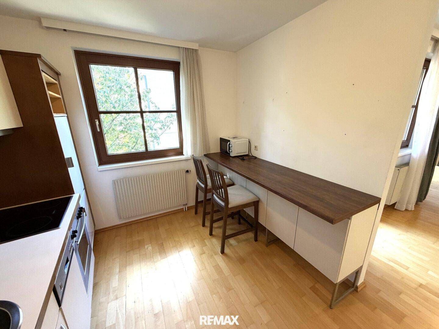Heller Küchenbereich mit Fenster, integriertem Essplatz und Mikrowelle für schnelle Mahlzeiten.