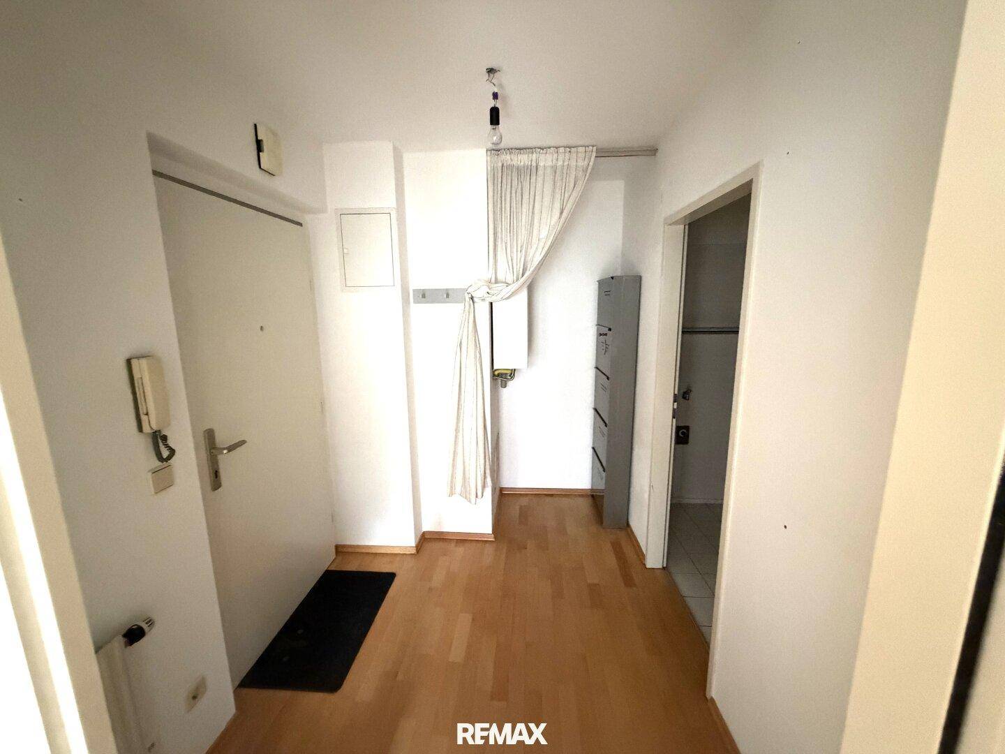 Eingangsbereich mit Holzboden und Garderobenbereich, führt zu weiteren Räumen der Wohnung.