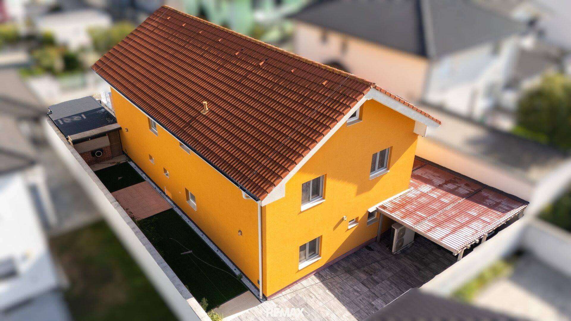 Rückansicht des Hauses mit orangerotem Ziegeldach und einem kleinen, gepflegten Gartenbereich.