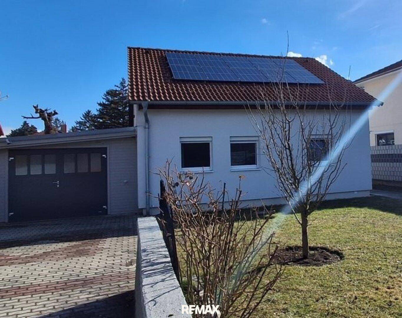 Seitenansicht des Hauses mit Solaranlage auf dem Dach und angrenzender Garage.