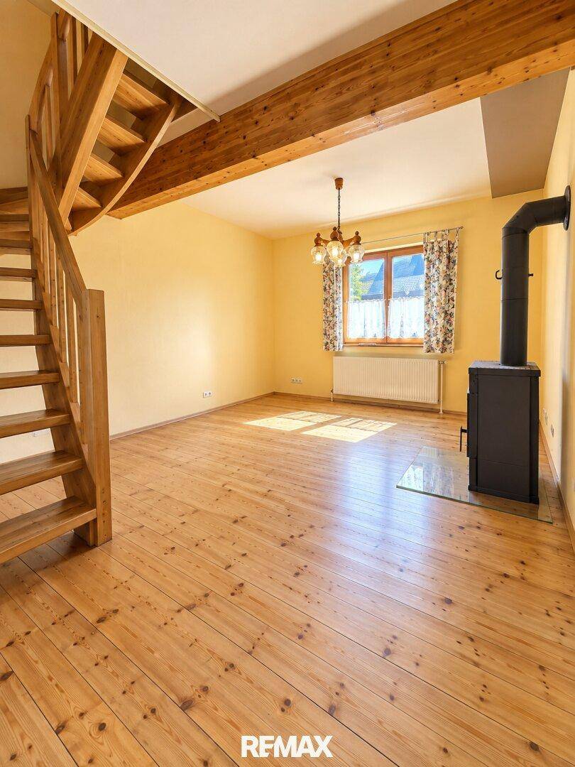 Gemütliches Wohnzimmer mit Holzdielenboden, Holztreppe und einem Kaminofen für wohlige Wärme.
