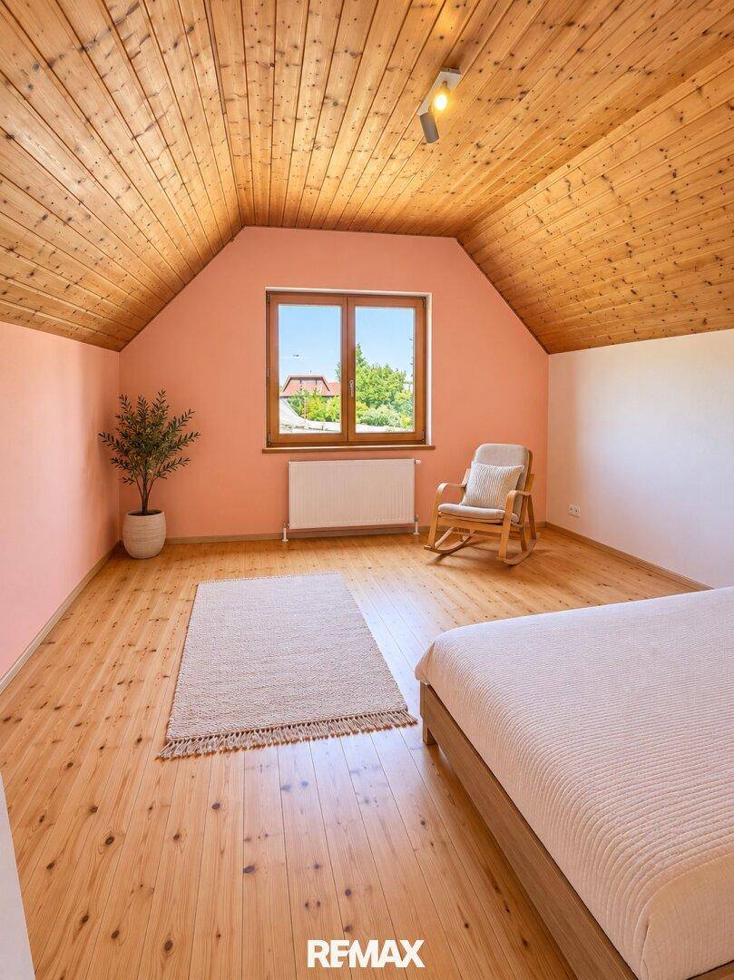 Helles Schlafzimmer mit Holzdielenboden, holzgetäfelter Decke und einem Fenster mit Ausblick.