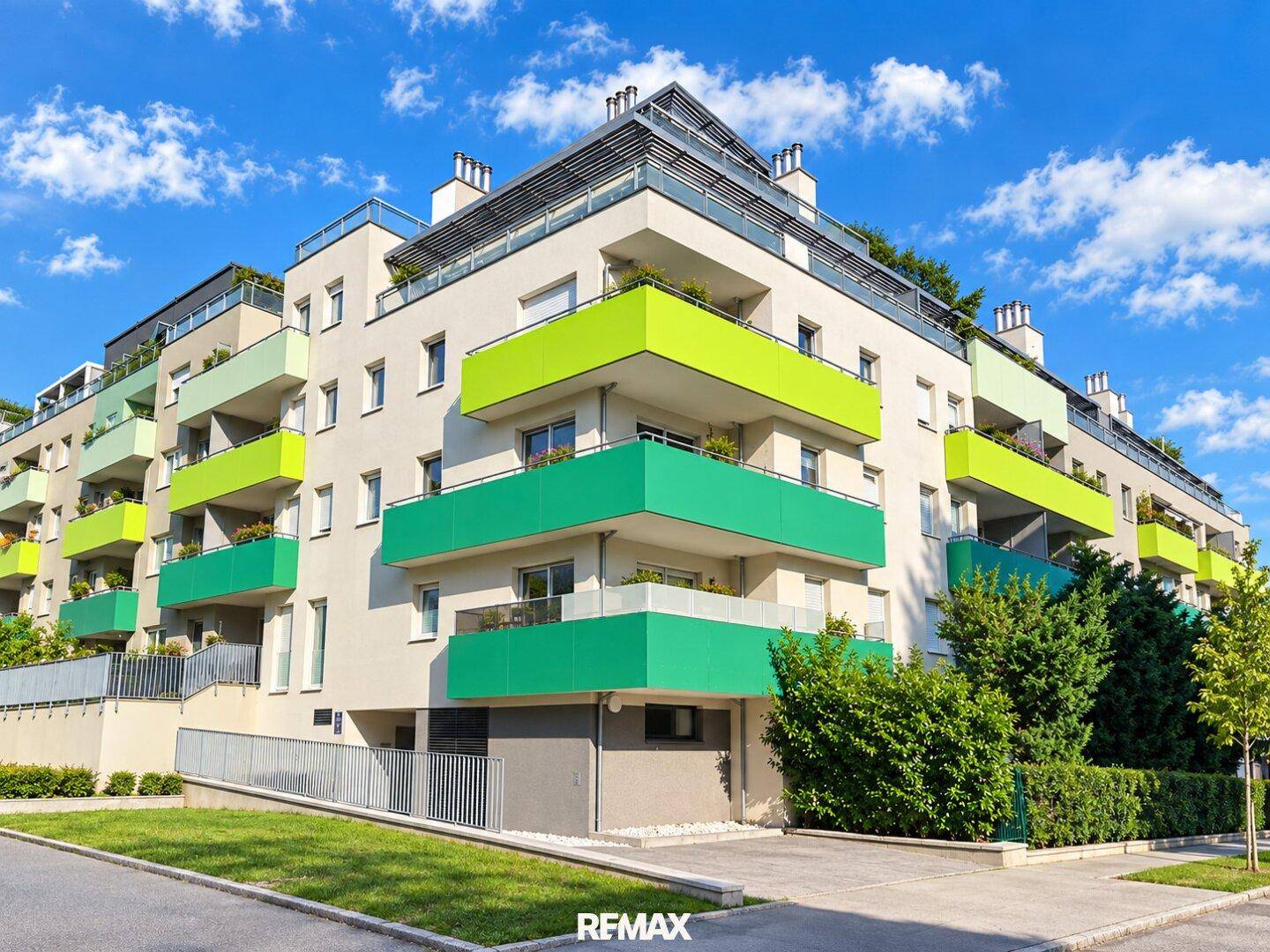 Moderne Wohnanlage mit farbigen Balkonen und zeitgenössischer Architektur unter blauem Himmel.