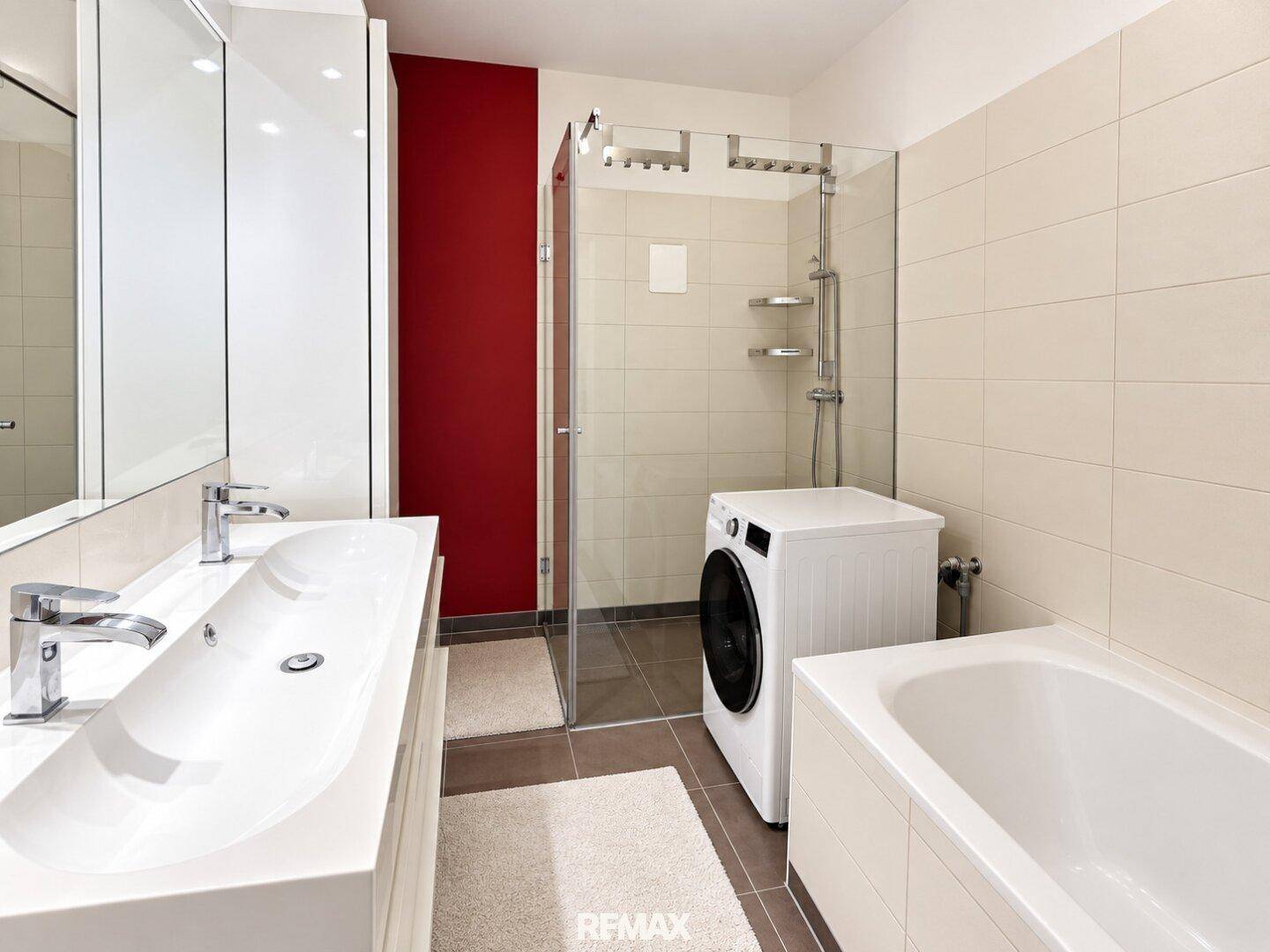 Geräumiges Badezimmer mit Doppelwaschbecken, Badewanne, Dusche und Waschmaschine.