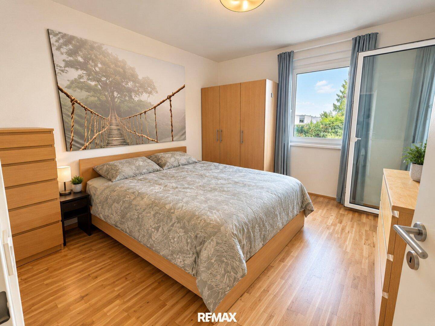 Helles Schlafzimmer mit Doppelbett, Holzmöbeln und großem Fenster mit Grünblick.