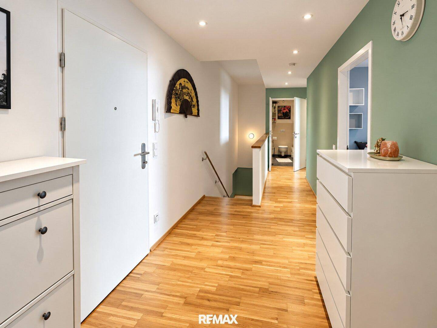 Geräumiger Flur mit Holzboden, Einbauschränken und Blick auf ein Badezimmer.