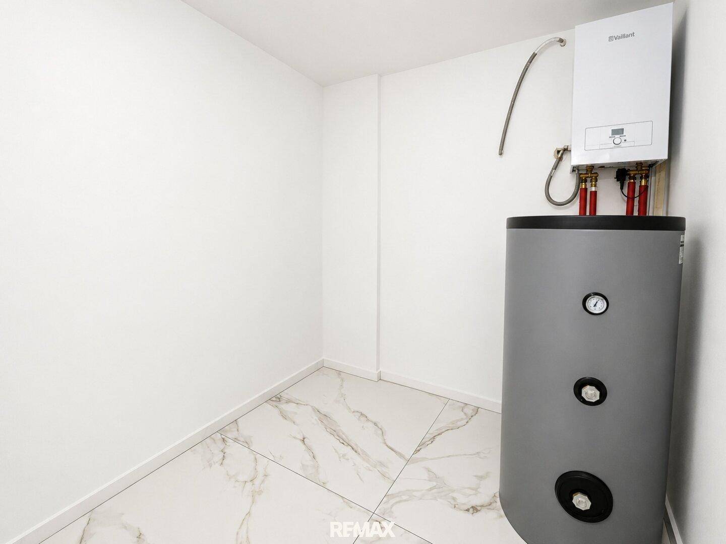 Praktischer Hauswirtschaftsraum mit Fliesenboden und Warmwasserbereiter für den täglichen Bedarf.
