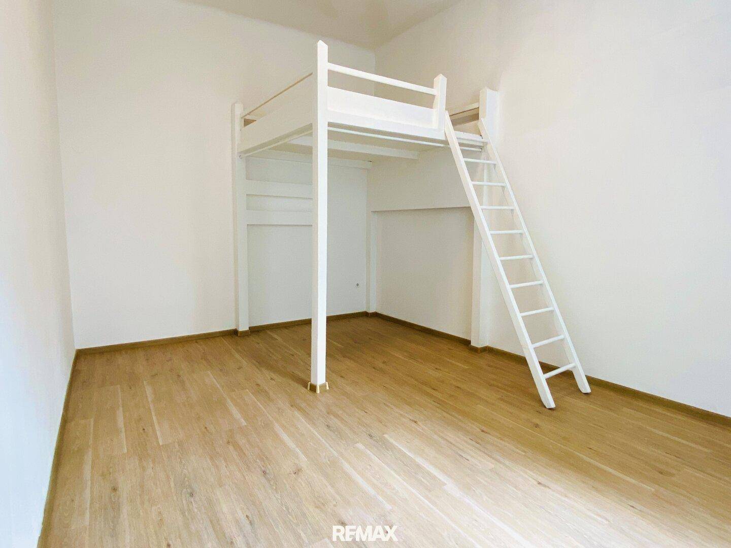 Geräumiges Zimmer mit weißem Hochbett und hellem Holzfußboden.