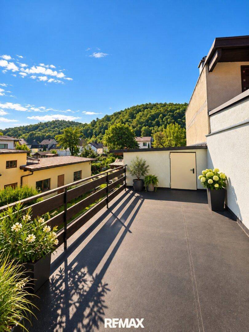 Geräumige Dachterrasse mit Holzzaun und Topfpflanzen, bietet einen weiten Blick auf grüne Hügel.