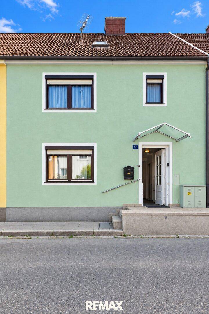 Fassade eines Hauses in hellem Grün mit Fenstern und einem einladenden Eingangsbereich.