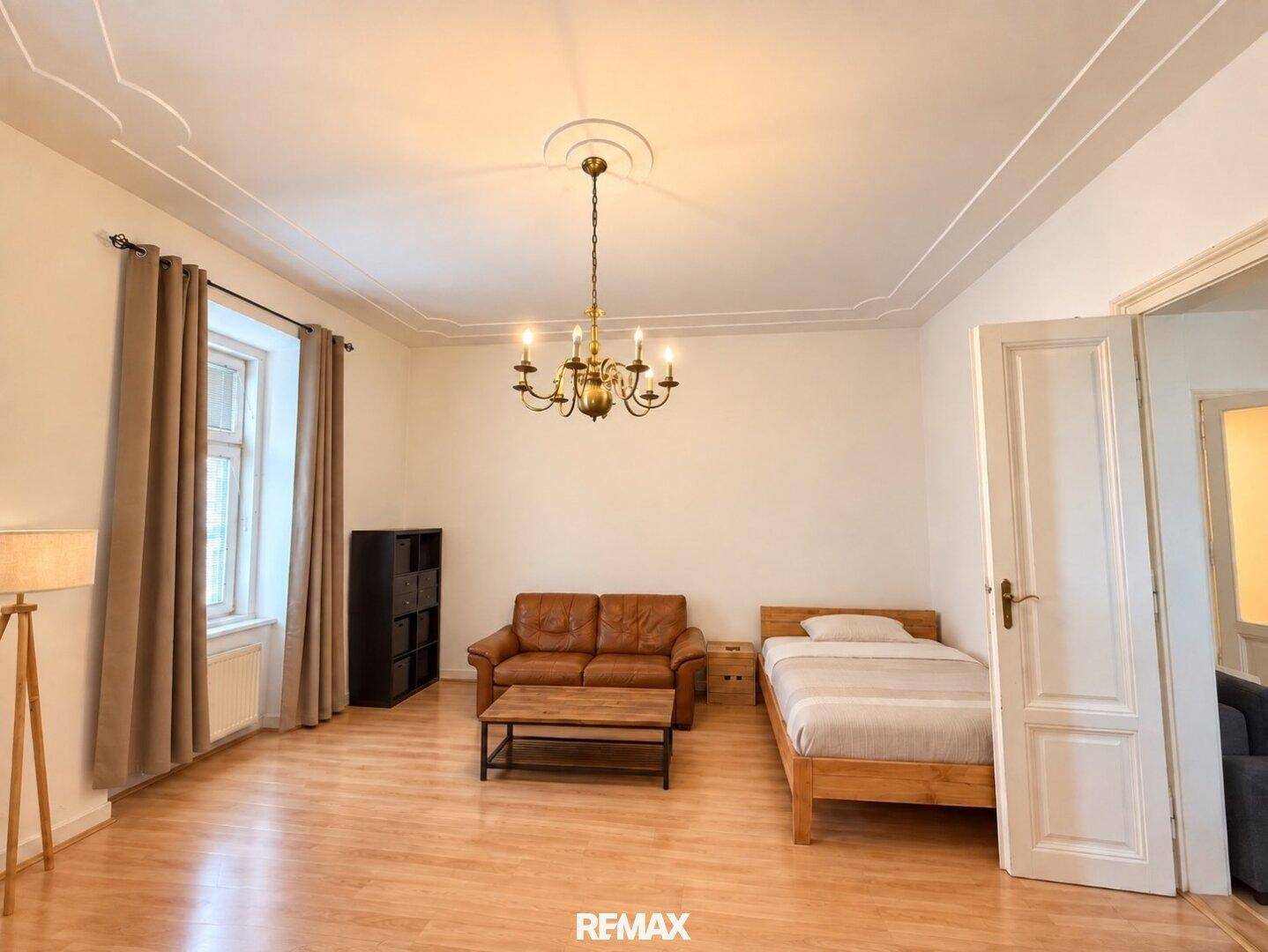 Helles Schlafzimmer mit Holzboden, Stuckdecke und klassischem Kronleuchter, bietet viel Platz.