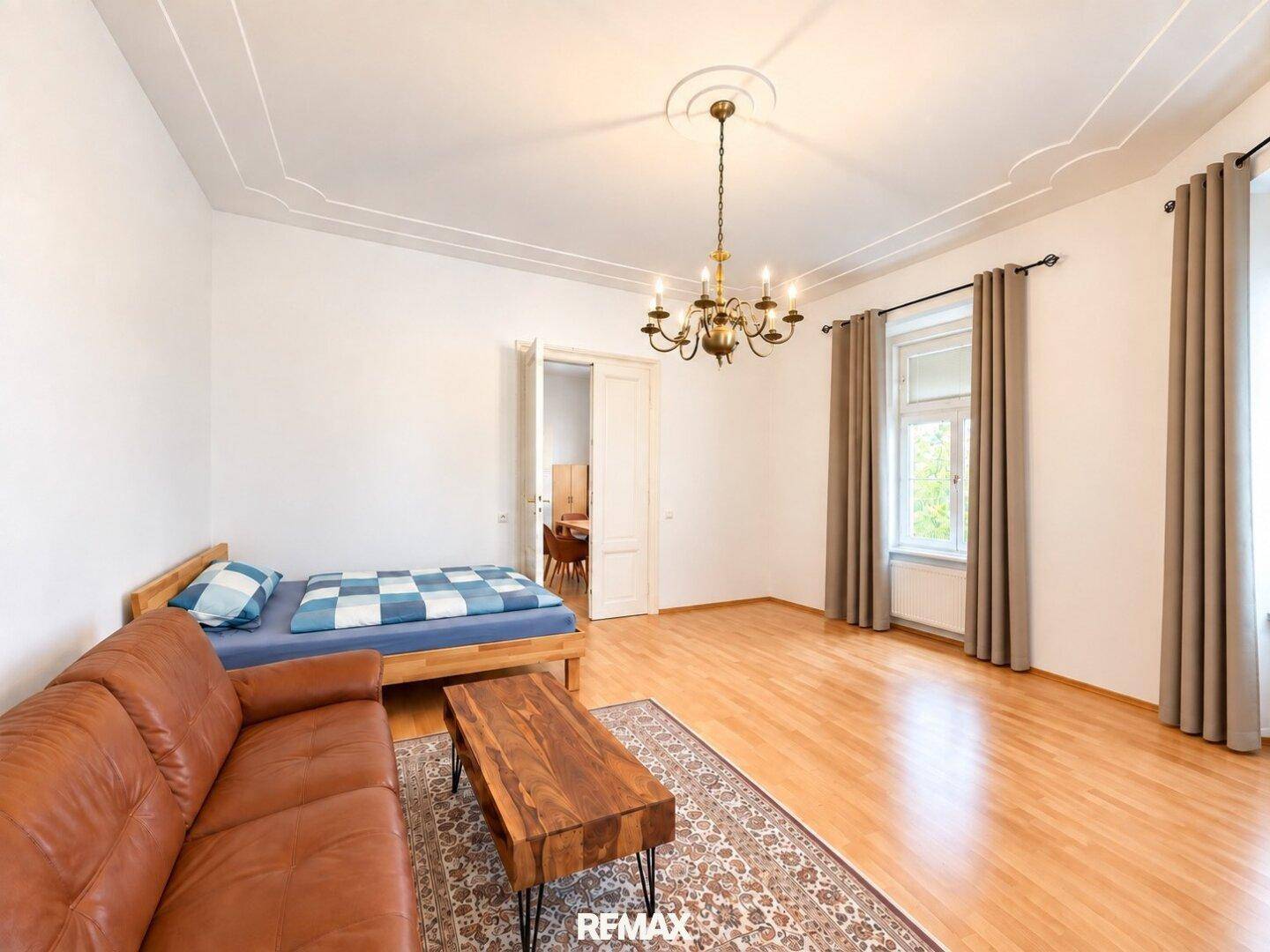 Großes Schlafzimmer mit Holzboden, Stuckdecke und Fenster mit Blick nach draußen.