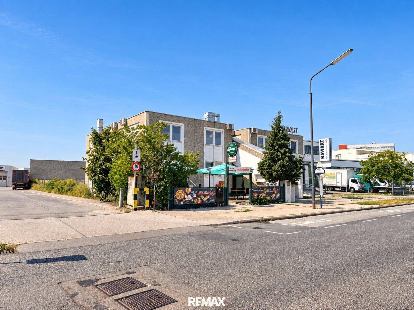 Seitenansicht des Gewerbegebäudes mit dem Asia Special Restaurant und einem Teil der Straße im Vordergrund.
