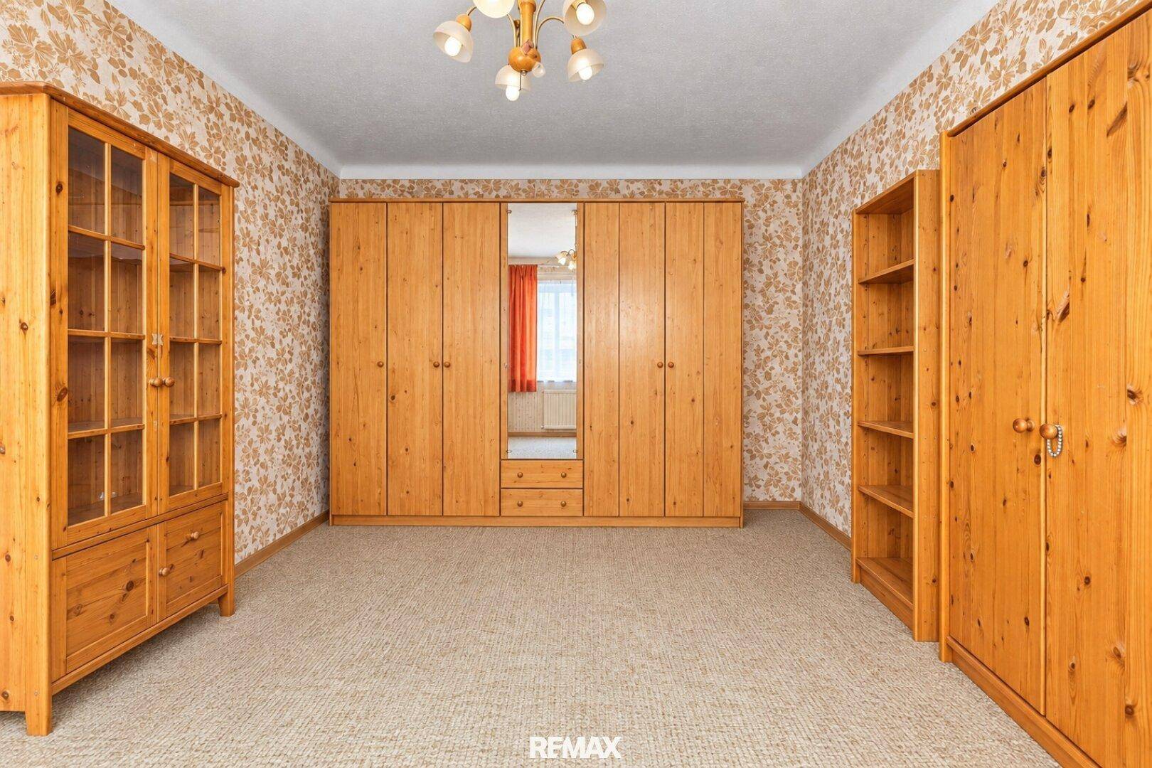 Geräumiges Schlafzimmer mit großen Holzschränken und Teppichboden.