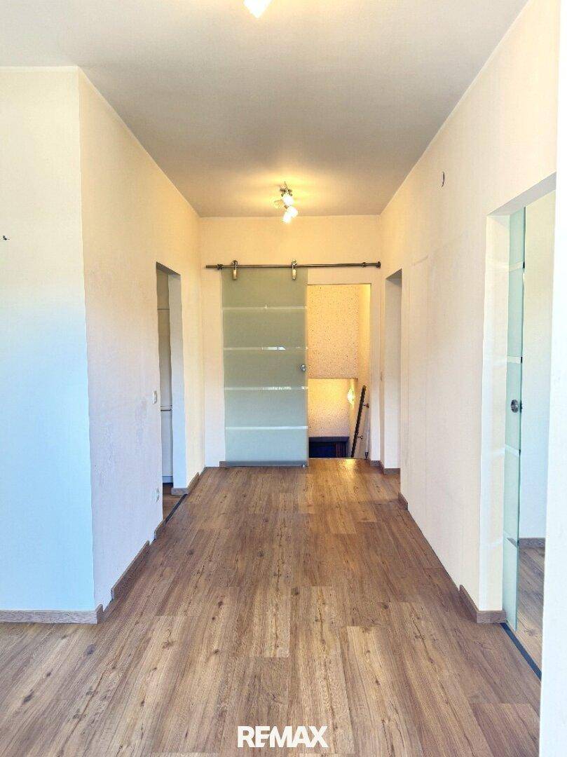 Heller Flur mit Laminatboden und einer modernen Glasschiebetür.
