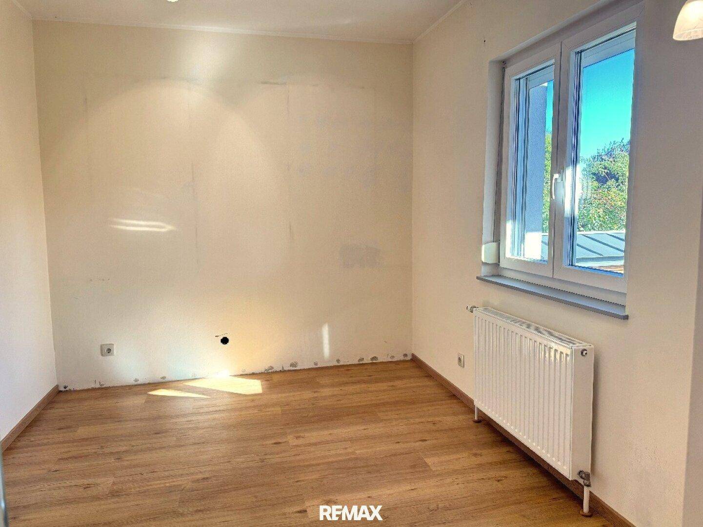 Freundliches Zimmer mit Laminatboden und großem Fenster, ideal als Schlaf- oder Arbeitszimmer.