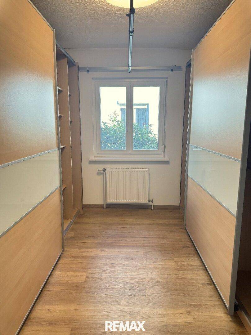 Zimmer mit beidseitigen Einbauschränken und Fenster, ideal als Ankleidezimmer.