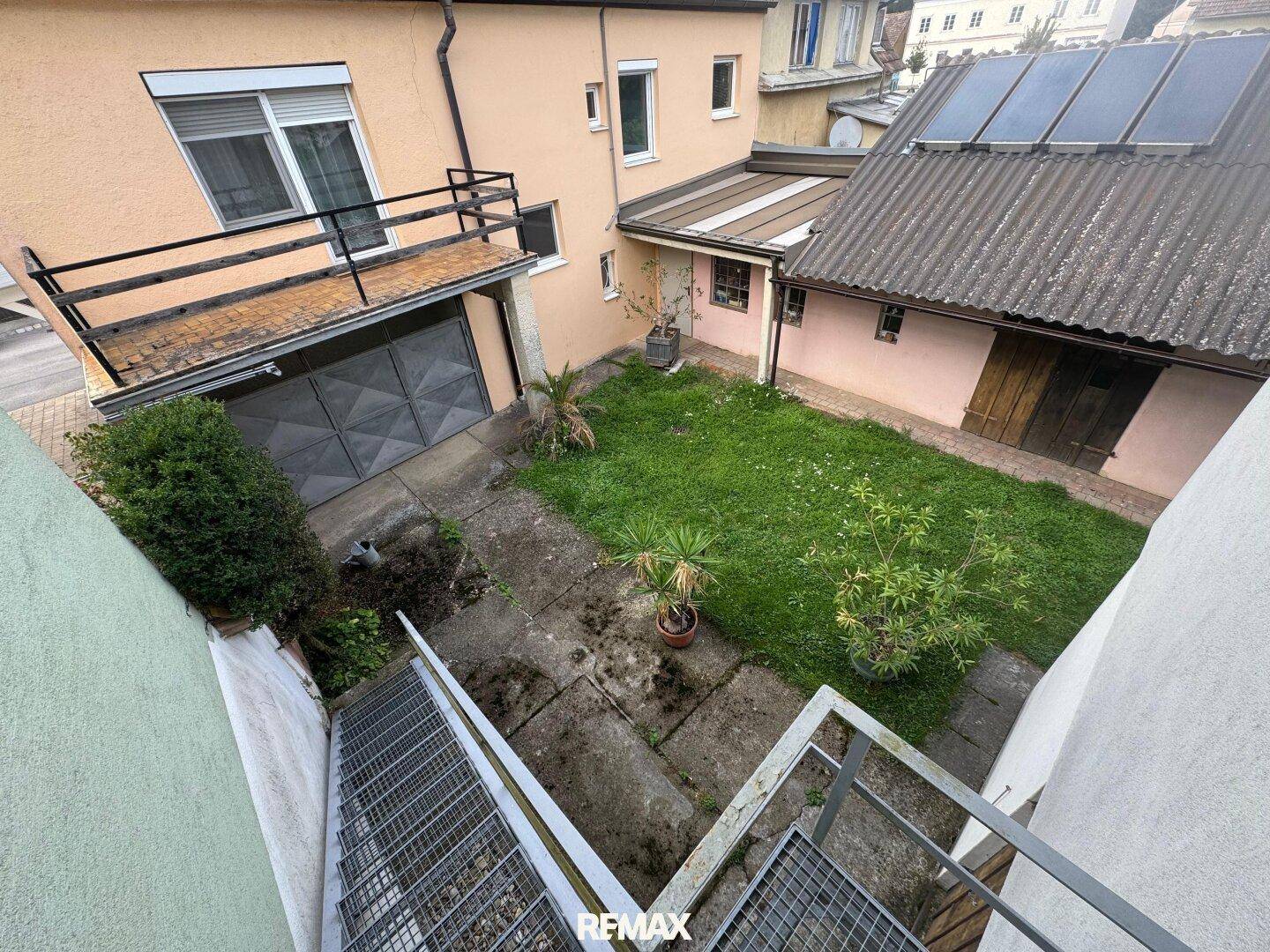 Blick von oben auf den Hinterhof mit Rasenfläche, Garage und Außentreppe.