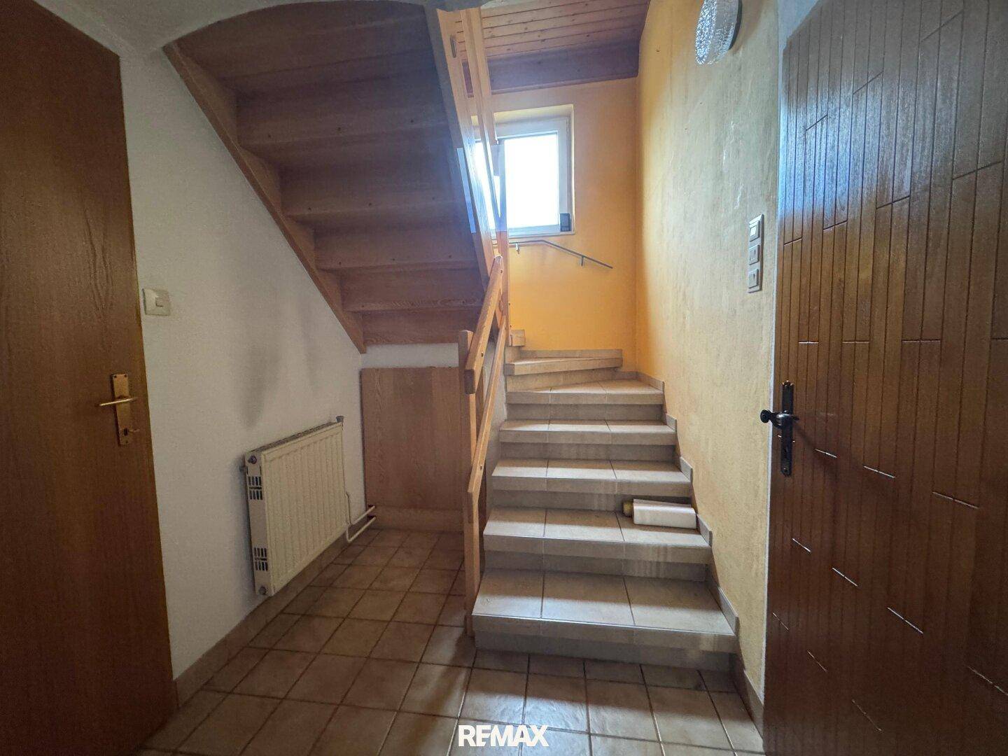 Eingangsbereich mit Treppe, Fliesenboden und Holztüren.