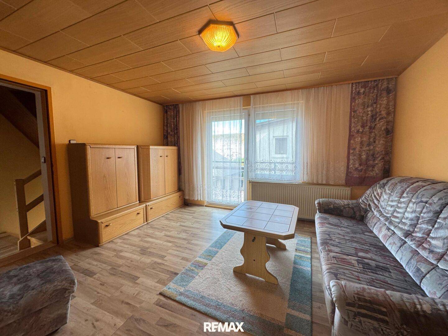 Helles Wohnzimmer mit Zugang zu einem kleinen Balkon und traditionellen Möbeln.